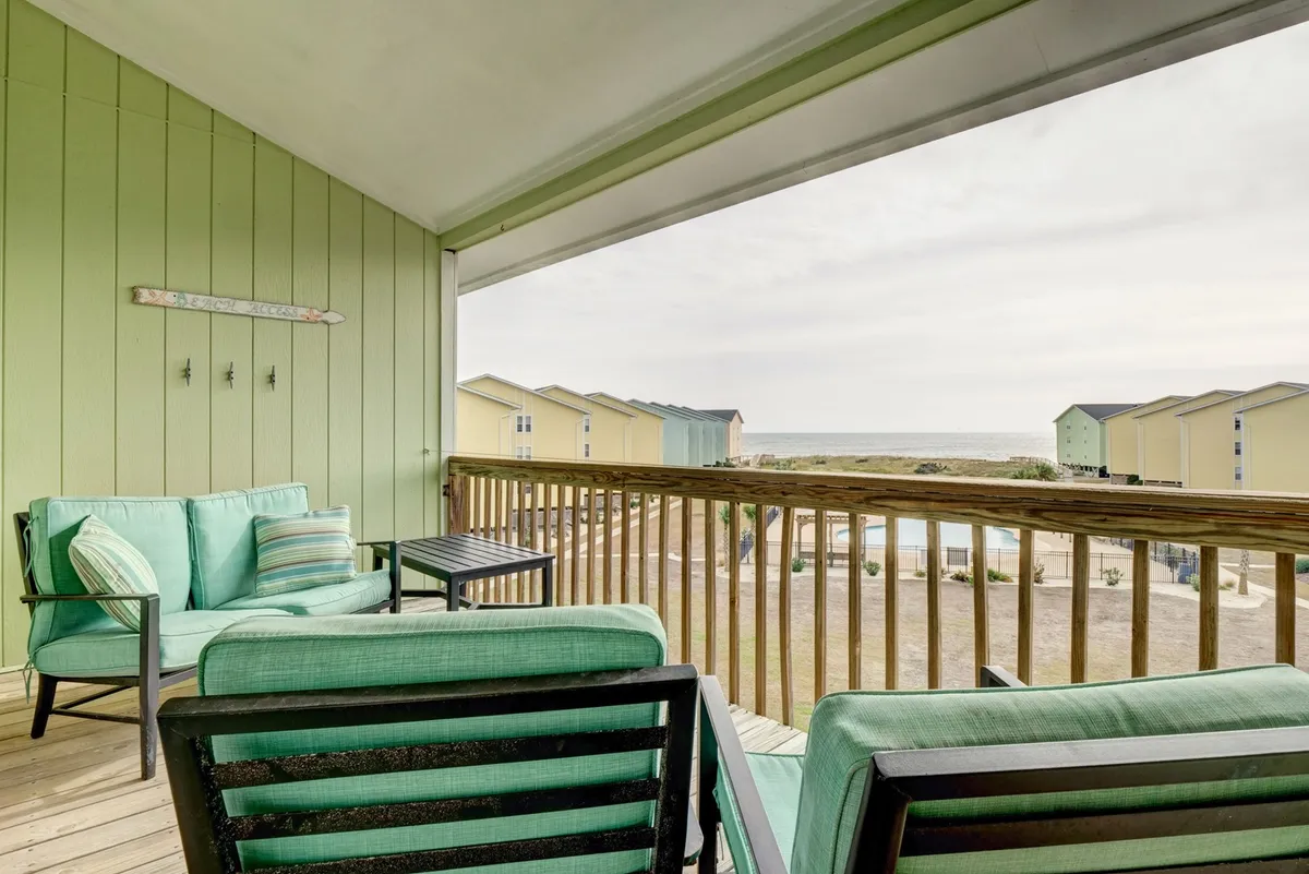 This exterior image captures a cozy seating area with views of the ocean and colorful beach houses. The arrangement invites moments of relaxation, people-watching, or planning a stroll to nearby attractions. The setting is tranquil and connected to the neighborhood vibe.